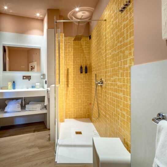 Salle de bain avec lavabo, miroir, serviettes et douche en verre.