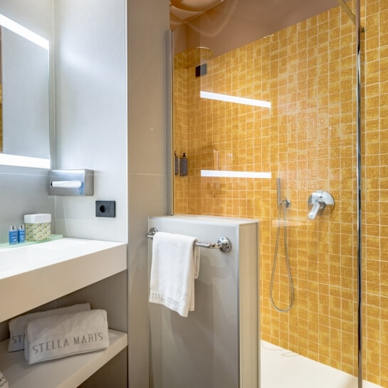 Salle de bain moderne avec miroir éclairé et douche en verre.
