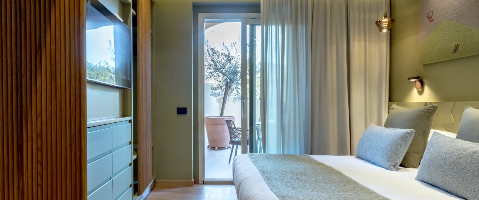 Hotelzimmer mit Bett, Holzschrank und Zugang zu einem Außenbereich.
