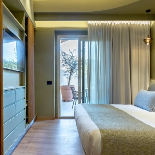 Chambre d'hôtel avec lit, placard et patio extérieur avec arbre.