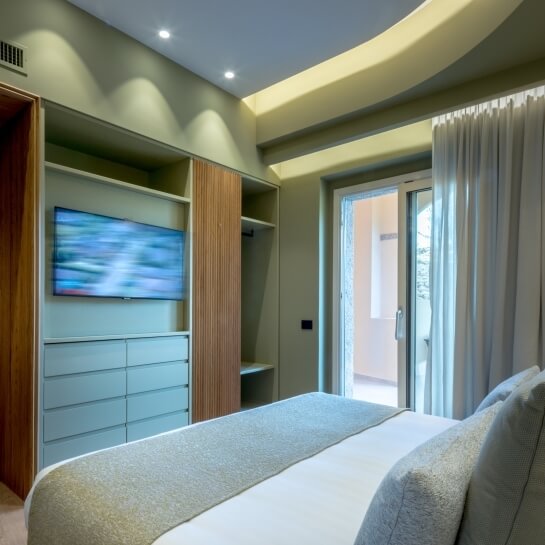 Chambre d'hôtel avec lit, télévision, armoire et porte-fenêtre.