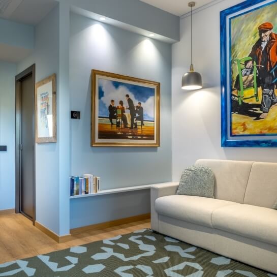 Chambre aux murs bleu clair, peintures, canapé et tapis géométrique.