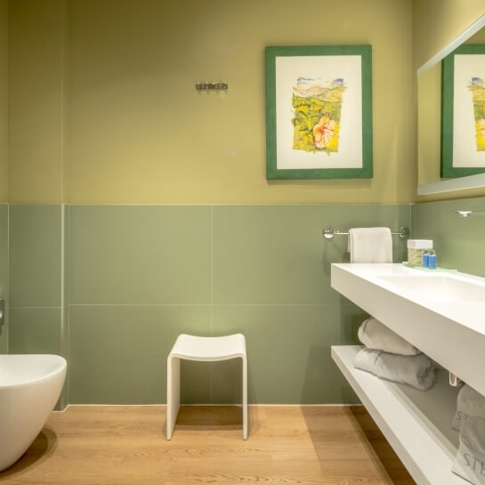 Salle de bain d'hôtel avec tabouret, vanité et serviettes.