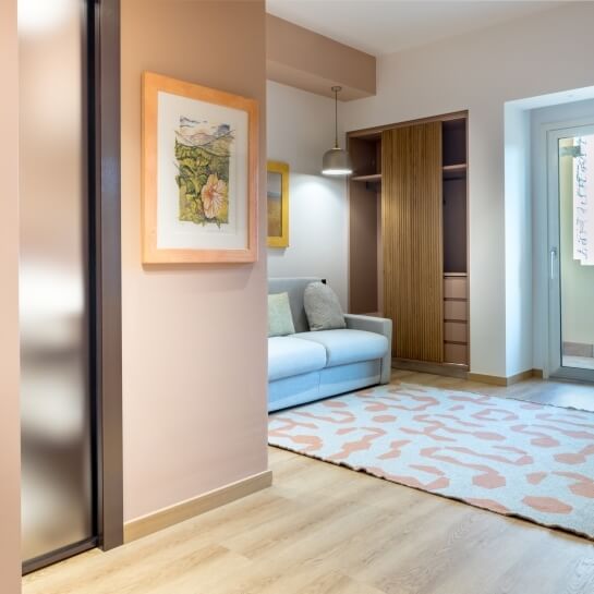 Chambre avec mur rose, canapé bleu, miroir jaune et œuvre d'art.