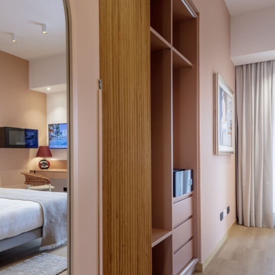 Chambre d'hôtel avec lit, miroir, bureau et armoire en bois.