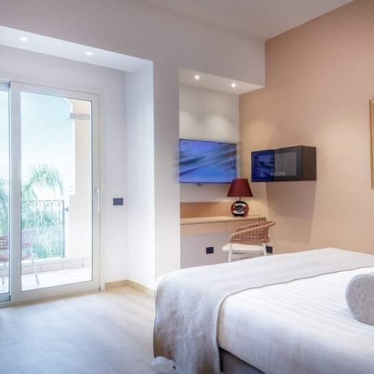 Chambre d'hôtel avec lit, bureau, télévision et balcon.