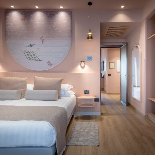 Chambre d'hôtel avec lit, œuvre d'art, et couloir adjacent.