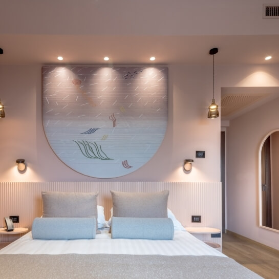 Chambre d'hôtel avec lit, œuvres d'art et éclairage moderne.