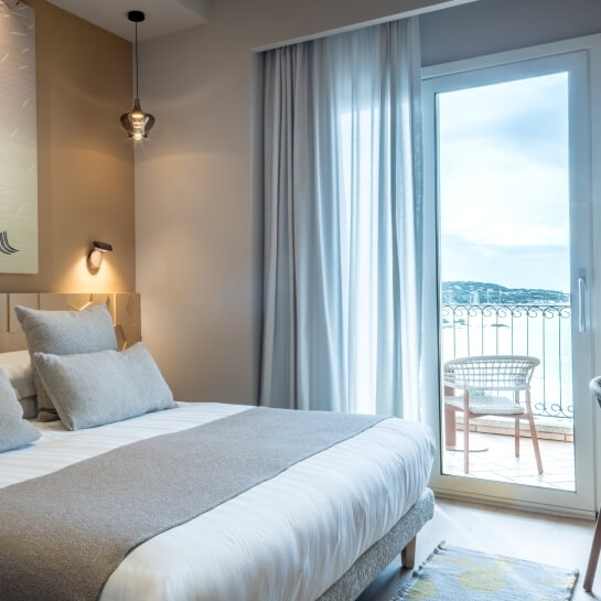 Chambre d'hôtel avec lit, peinture, balcon et lumière suspendue.