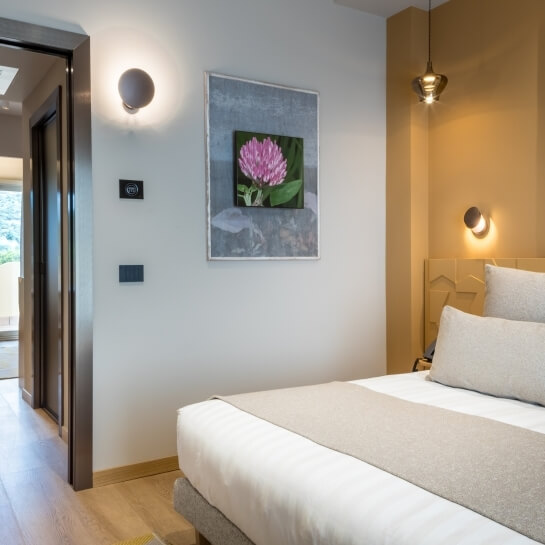 Chambre d'hôtel avec lit, œuvre d'art florale et luminaire suspendu.