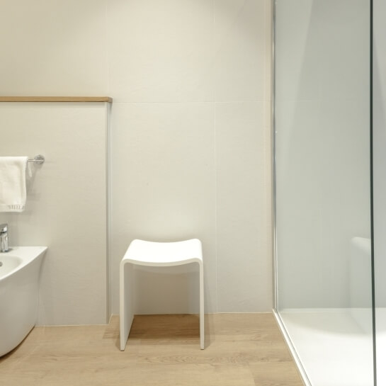 Tabouret blanc sur un sol en bois, salle de bain moderne.