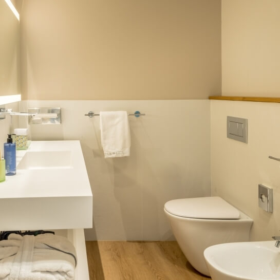 Salle de bain avec lavabo, toilettes, bidet et serviette accrochée.