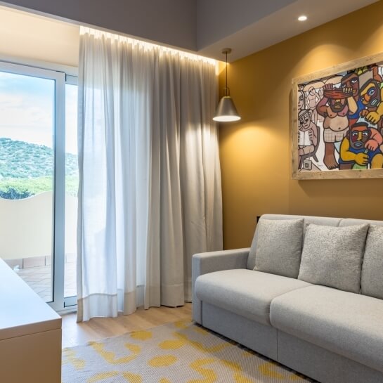 Chambre d'hôtel avec canapé gris, tapis jaune et peinture colorée.