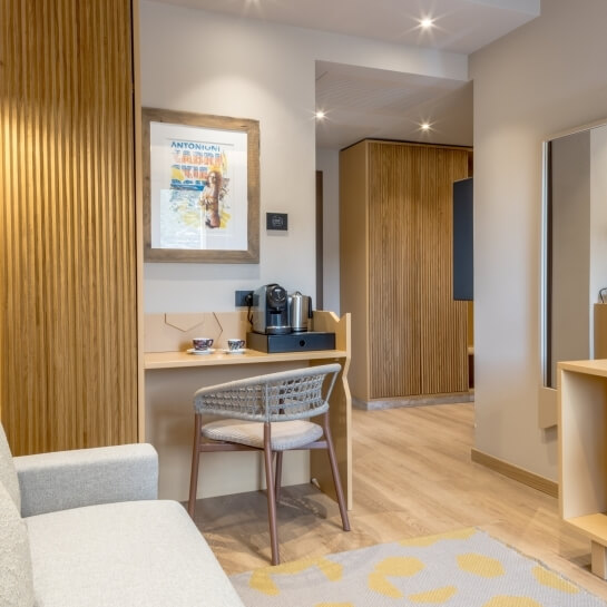 Chambre d'hôtel avec canapé, bureau en bois et miroir.