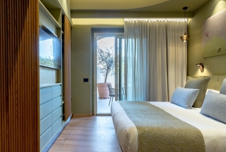 Chambre d'hôtel avec lit, télévision, et portes-fenêtres vers patio.