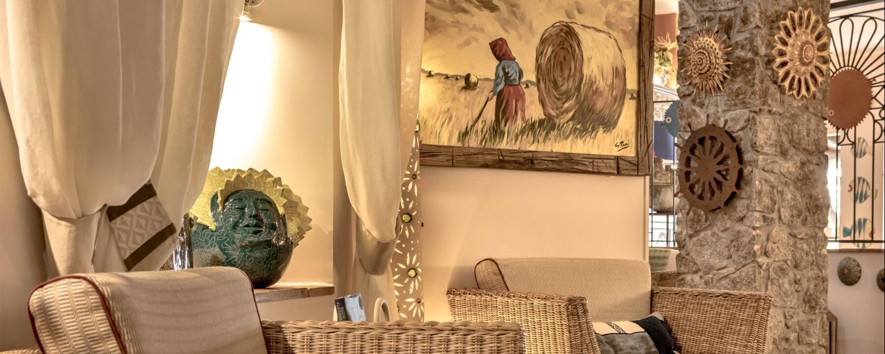 Intérieur serein avec des chaises en osier, tapis beige, peinture rustique et éclairage doux, créant une ambiance chaleureuse.