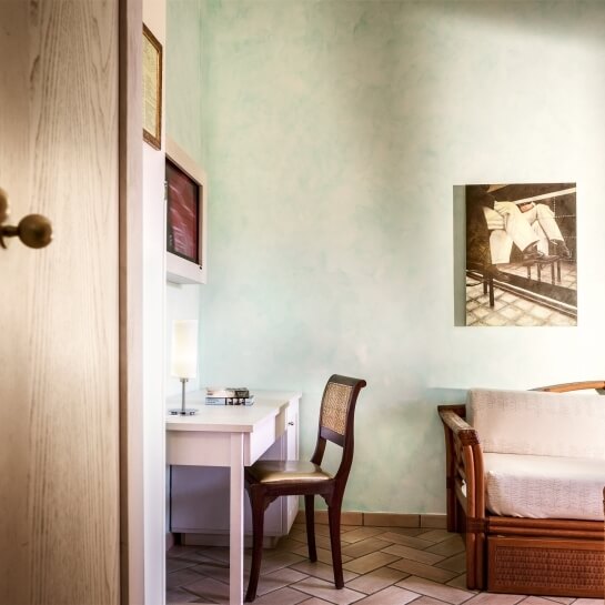 Una stanza con pareti verdi, mobili bianchi, un letto in vimini e illuminazione calda, perfetta per il relax.