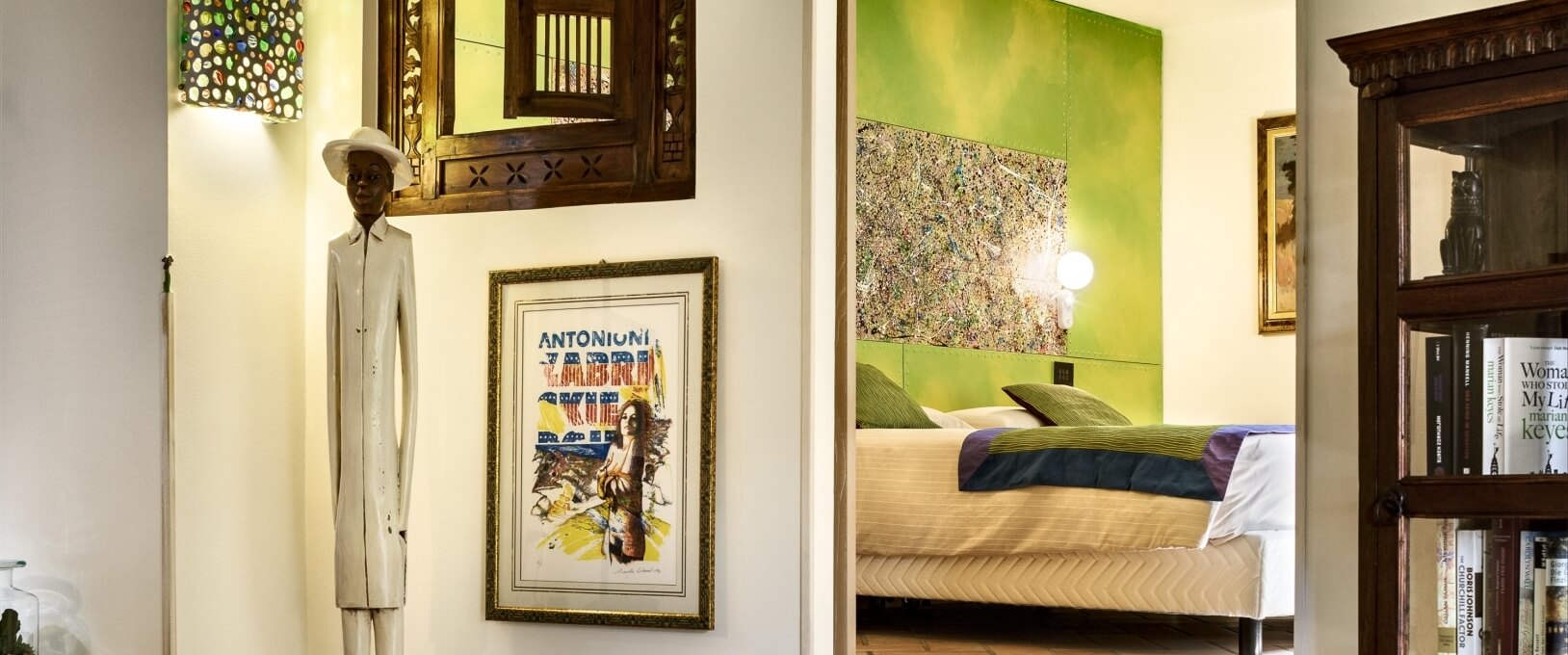 Chambre élégante avec sculpture blanche, miroir, affiche, lit plateforme et peinture abstraite, décorée dans des tons terreux.